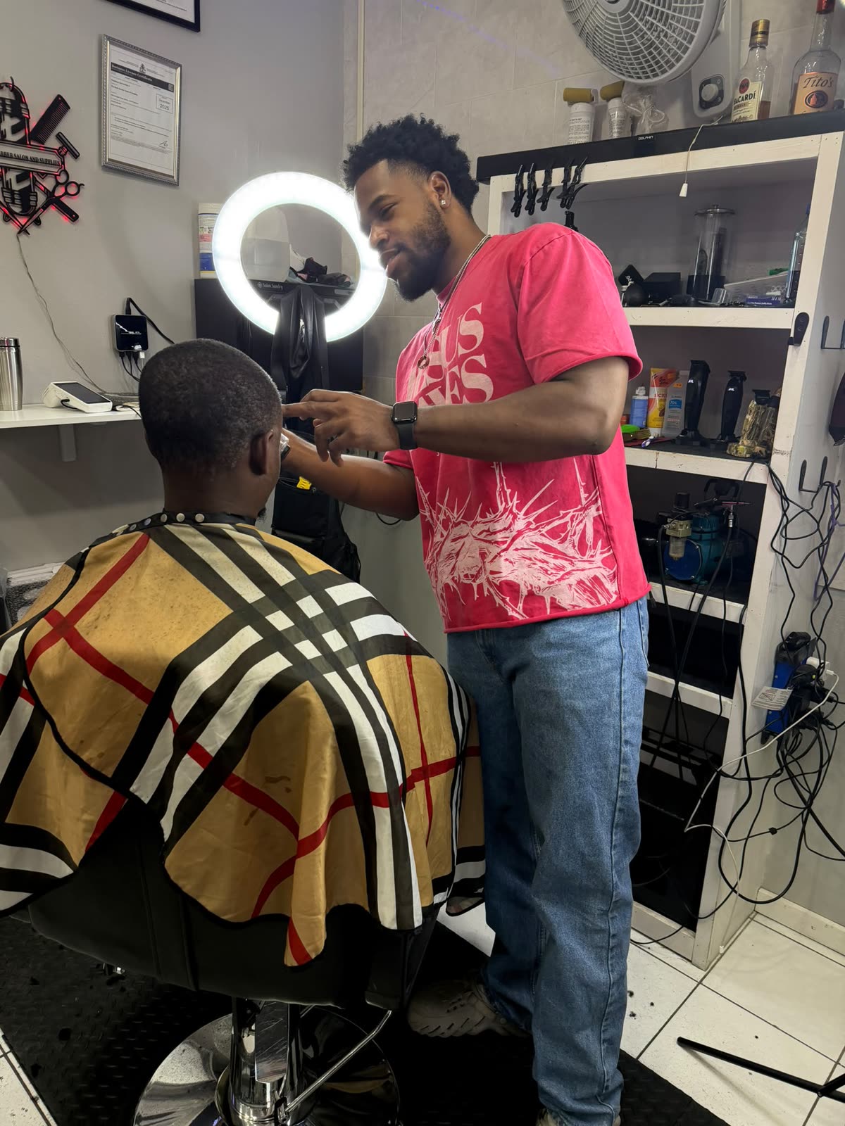 A Duch Barber barber finishing a client's cut under the ring light